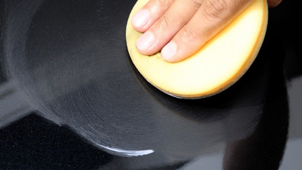 Hand applying polish on black car