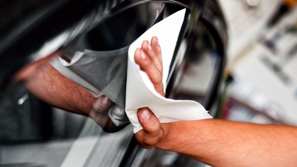 auto car worker and mechanic cleaning a cars window with special tool for scratches and wiper