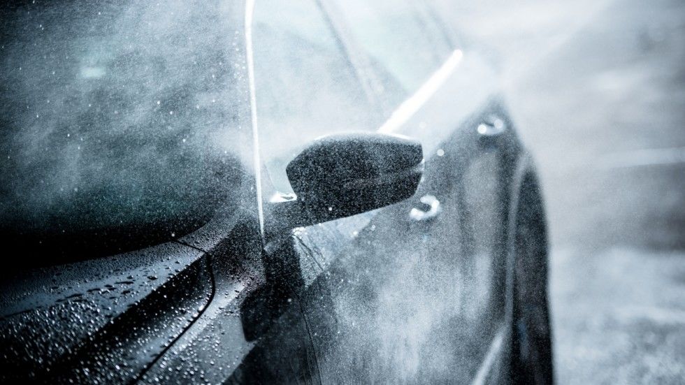 Gentle Car Washing. Modern Compact Car Covered by Water. Dark Blue Color Grading.