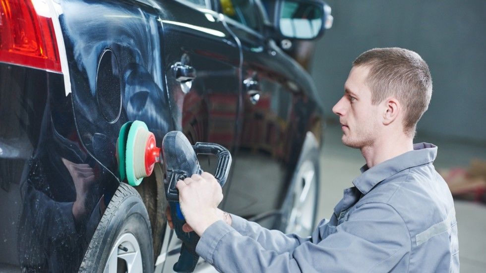 Auto body repairs. Mechanic worker burnish and polishing automobile car body by buffing grinding...
