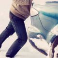 closeup of man pushing car stuck in snow